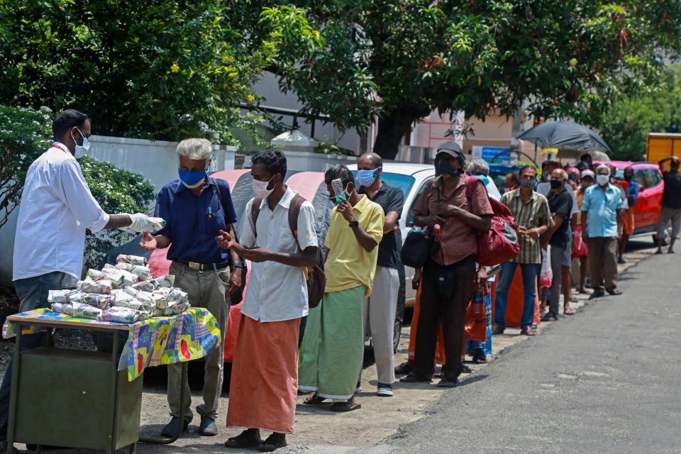 A member (L) of a non-governmental organisation (NGO) distributes free food packets to the needy people amid Covid-19 coronavirus pandemic in Kochi on May 7, 2021. (Photo by Arunchandra BOSE / AFP) (Photo by ARUNCHANDRA BOSE/AFP via Getty Images)