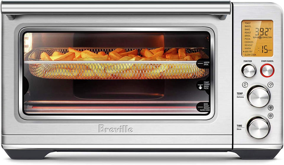 A stainless steel air fryer oven with french fries inside. 