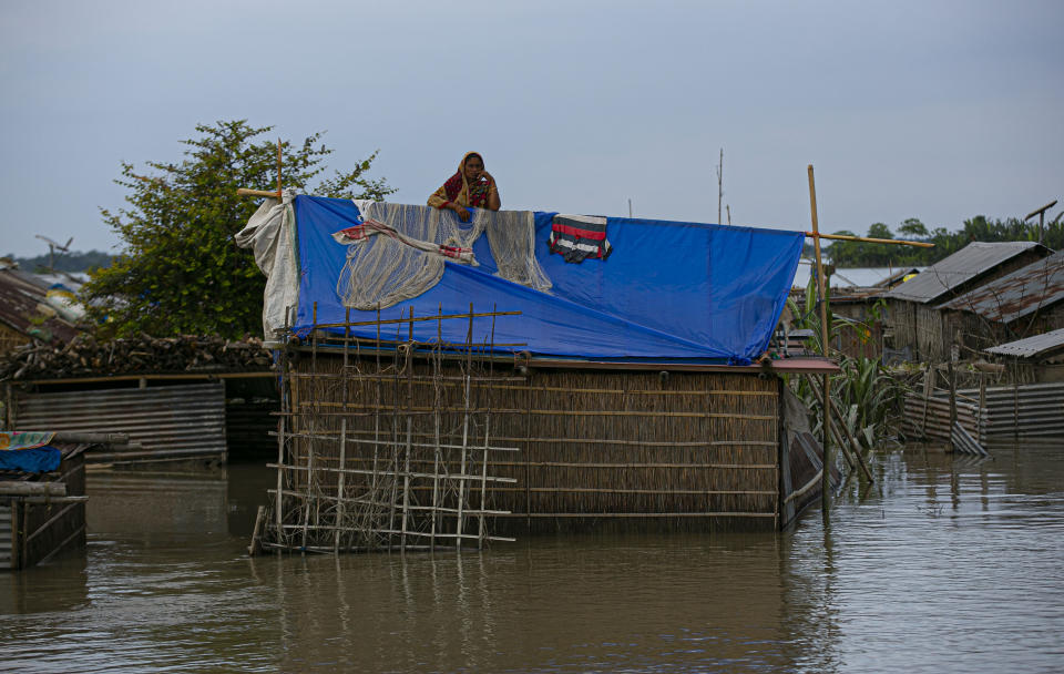 A flood affected Indian woman stands on the roof of her partially submerged house along river Brahmaputra in Morigaon district, Assam, India, Thursday, July 16, 2020. Floods and landslides triggered by heavy monsoon rains have killed dozens of people in this northeastern region. (AP Photo/Anupam Nath)
