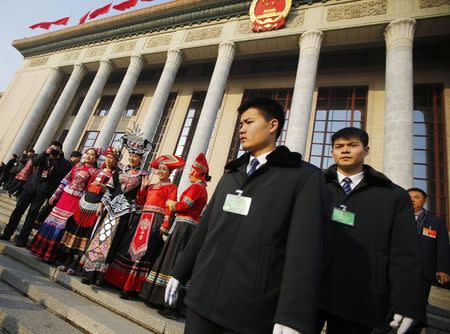 Ethnic minority delegates pose for pictures next to security officers ahead of the opening of the annual full session of the National People's Congress, the country's parliament, in front of Great Hall of the People at the Tiananmen Square in Beijing March 5, 2015. REUTERS/Carlos Barria