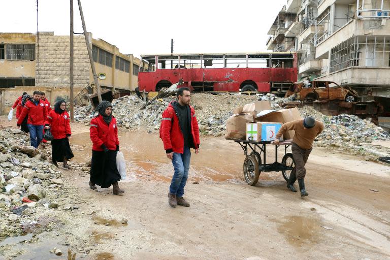 Members of the Syrian Red Crescent cross on February 21, 2015, between a regime held area to a rebel-controlled area in Aleppo's Bustan al-Qasr district, to deliver aid for school children