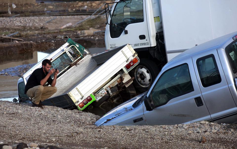 Emil Motycka takes pictures of his flooded trucks in Longmont, Colorado September 16, 2013. Seven people were confirmed dead and at least 1,500 homes destroyed in Colorado after a week of rare, torrential rains along the eastern slopes of the Rockies, and helicopter search-and-rescue flights resumed on Monday in flood-stricken areas. (REUTERS/Rick Wilking)