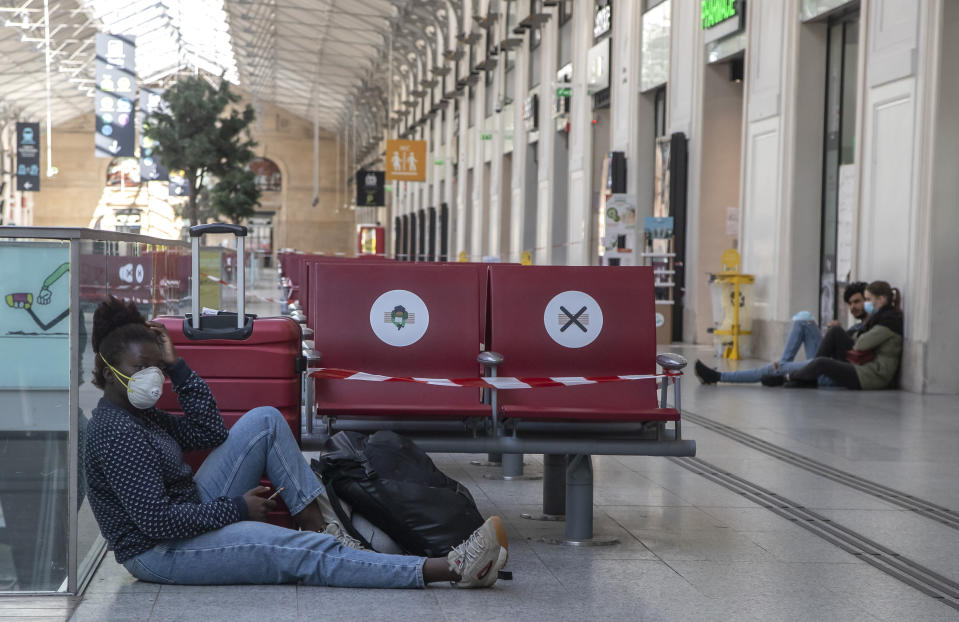 A woman wears a mask to protect against the spread of the coronavirus as she sits next to her luggages at the Gare Saint Lazare train station in Paris, Wednesday, May 6, 2020. France prepares to lift its strict nationwide lockdown on May 11, 2020. (AP Photo/Michel Euler) he