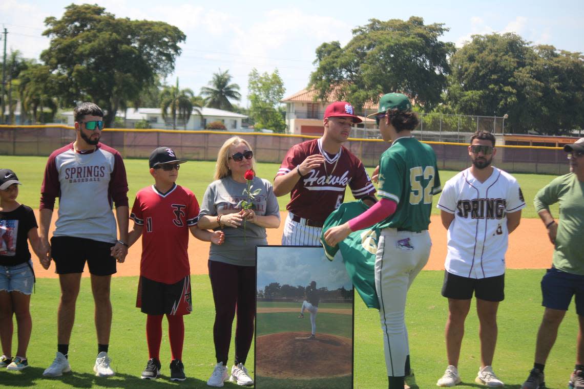 Mater Academy’s Dylan Fernandez presents Miami Springs pitcher Brandon Olivera with the jersey his father, Isaul, wore while he was an assistant coach at Mater Academy. Isaul died suddenly this past January and both schools honored him during Miami Springs’ Senior Day ceremony on April 27.