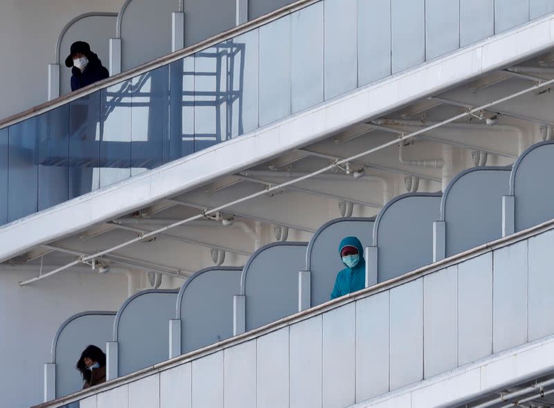 Passengers look out from their cabins as the cruise ship Diamond Princess, where 10 people on the ship had tested positive for coronavirus yesterday, arrives at Daikoku Pier Cruise Terminal in Yokohama