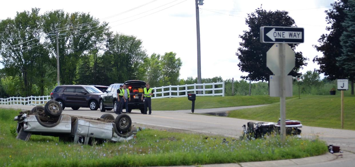 An overturned pickup and a motorcycle are seen after they collided on Oconto County J along U.S. 41 south of Oconto on Aug. 14, 2019. The motorcyclist, Albert Reppert of Illinois, died after the crash. Looking on are officers of the Oconto County Sheriff's Office and the Wisconsin State Patrol.