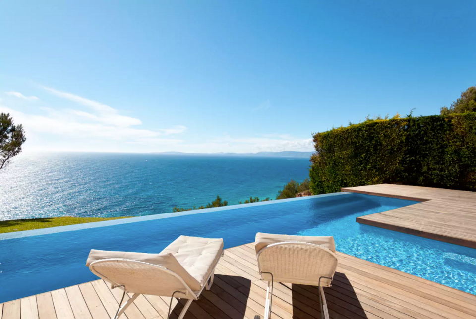 <p>This architectural gem boasts a private infinity pool with dazzling views of the ocean. The pool itself is massive with the upper level including a jacuzzi and the second T-shaped part (seen here) is surrounded by a wood deck with sun loungers. The water cascades from the upper to lower level through a serene waterfall. (Airbnb) </p>