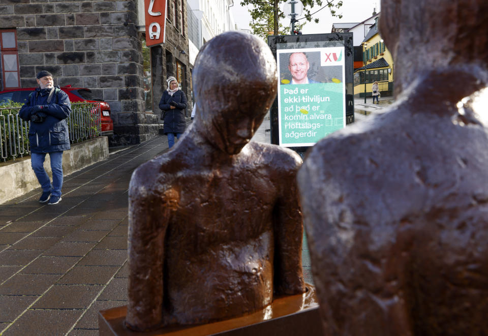 People walk past an election poster from the Left Green Party, saying "It isn't coincidence that the climate issues are taken seriously" in Reykjavik, Iceland, Wednesday, Sept. 22, 2021. (AP Photo/Brynjar Gunnarsson)