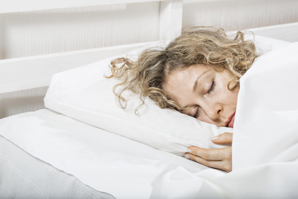 A blonde woman sleeps soundly on her side, with her face pressed into the pillow