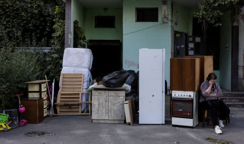 A woman sits next to her belongings from her destroyed apartment as she waits for the rented vehicle for a transport in Saltivka neighbourhood of Kharkiv