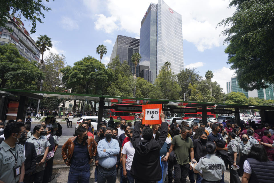 People stand outside after a magnitude 7.6 earthquake was felt in Mexico City, Monday, Sept. 19, 2022. The sign is for people from the fourth floor of a nearby building to gather there. The quake hit at 1:05 p.m. local time, according to the U.S. Geologic Survey, which said it was centered near the boundary of Colima and Michoacan states. (AP Photo/Fernando Llano)