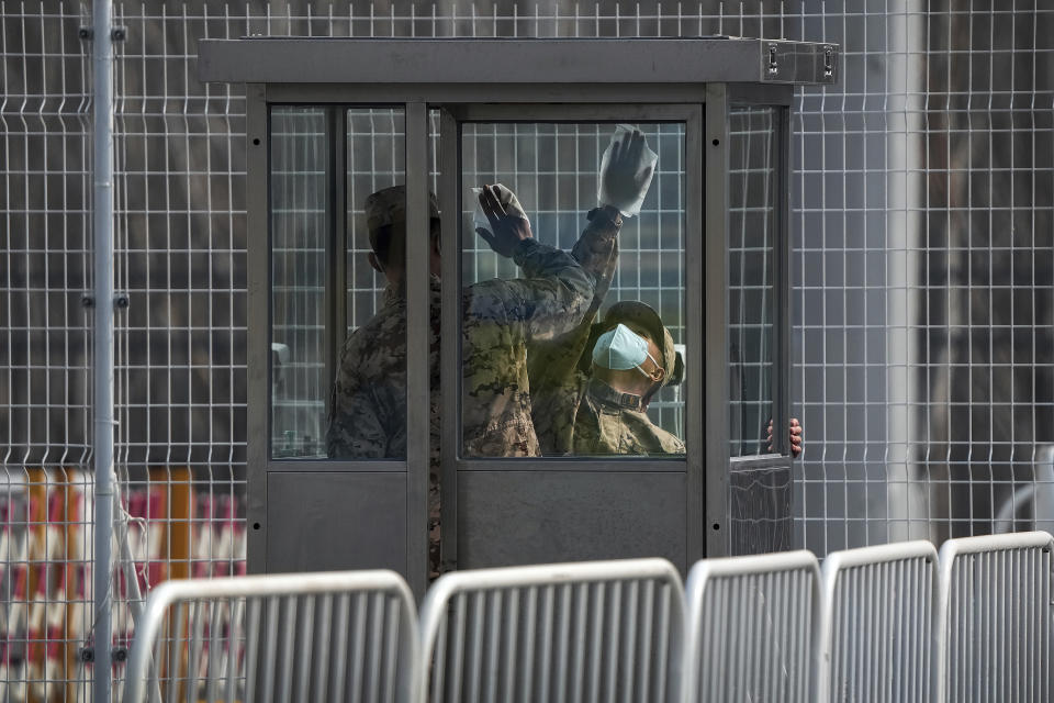 Soldiers wearing face masks to help protect from the coronavirus disinfectant a paramilitary police guard post at an interchange bus stopping point during the 2022 Winter Paralympics, Wednesday, March 9, 2022, in the Yanqing district of Beijing. (AP Photo/Andy Wong)