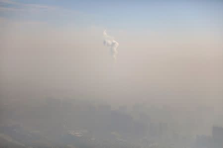 A chimney of a power plant is pictured among smog as a red alert for air pollution is issued in Beijing. REUTERS/Stringer