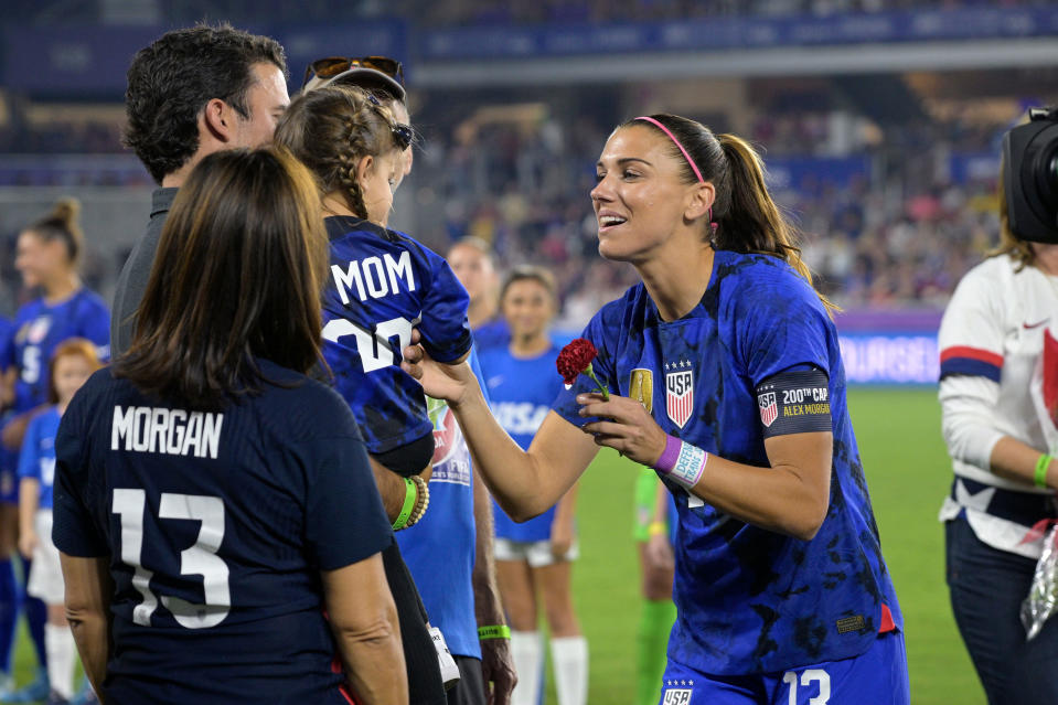 Alex Morgan receives a flower from her daughter Charlie, with husband Servando Carrasco, while being honored for her 200th appearance for the U.S. women’s national team before a SheBelieves Cup match against Canada, in Orlando, Fla., on Feb. 16, 2023.<span class="copyright">Phelan M. Ebenhack—AP</span>