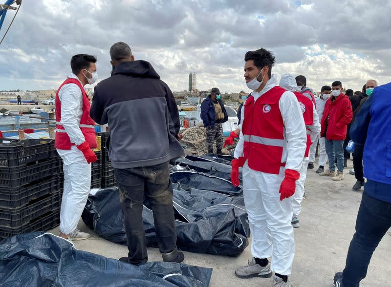 Libyan Red Crescent workers put the body of a migrant, who died after their boat capsized, in a bag, in Garabulli