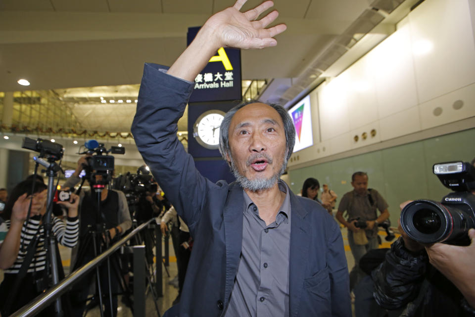 Chinese dissident writer Ma Jian waves to media after arriving Hong Kong international airport, Friday, Nov. 9, 2018. Despite Mallet's rejection, Hong Kong on Friday permitted dissident writer Ma to enter to attend a literary festival, even after an arts venue in the city canceled his appearance. Ma, whose novels frequently satirize China's communist leaders, told reporters he experienced nothing unusual while passing through passport control and that organizers were still lining-up a place for him to speak. "The lecture will definitely happen. If there is a single Hong Kong person who is willing to listen, or a single reader who contacts me, I will be there," Ma said. (AP Photo/Kin Cheung)