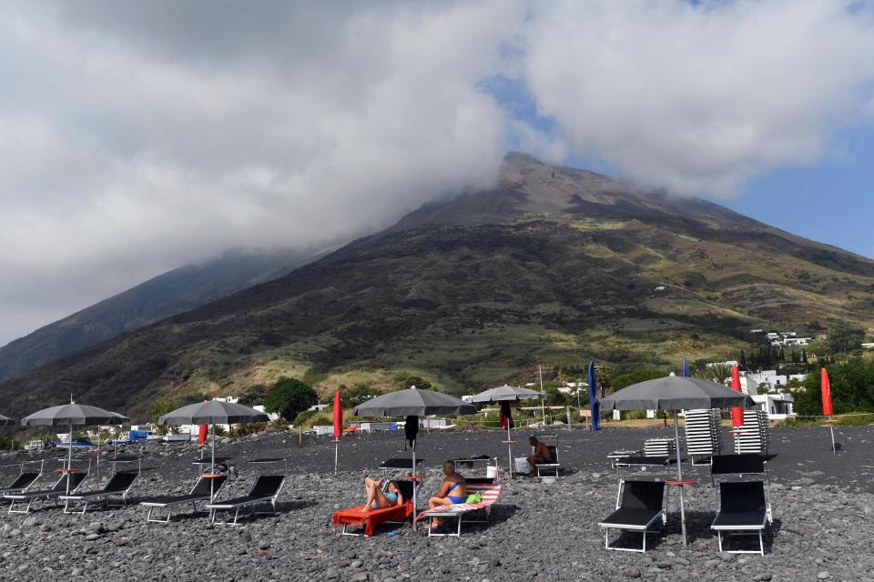 Sunbathers enjoy a day on the beach in front of the volcano in the island of Stromboli, Italy, Friday, July 5, 2019. 