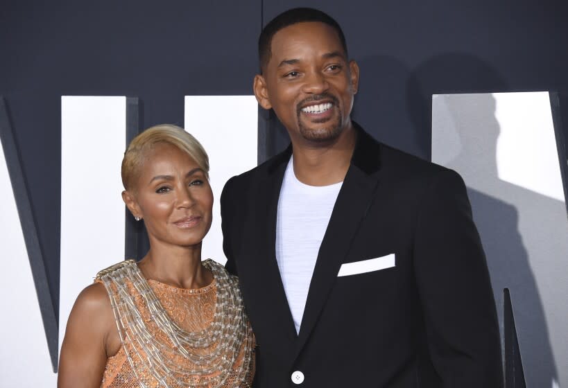 A woman with short, blond hair posing next to a man with short, black hair