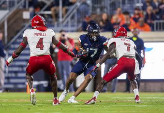 Virginia wide receiver JR Wilson (17) tries to get away from North Carolina State defenders Cecil Powell (4) and Shyheim Battle (7) during the first half of an NCAA college football game Friday, Sept. 22, 2023, in Charlottesville, Va. (AP Photo/Mike Caudill)