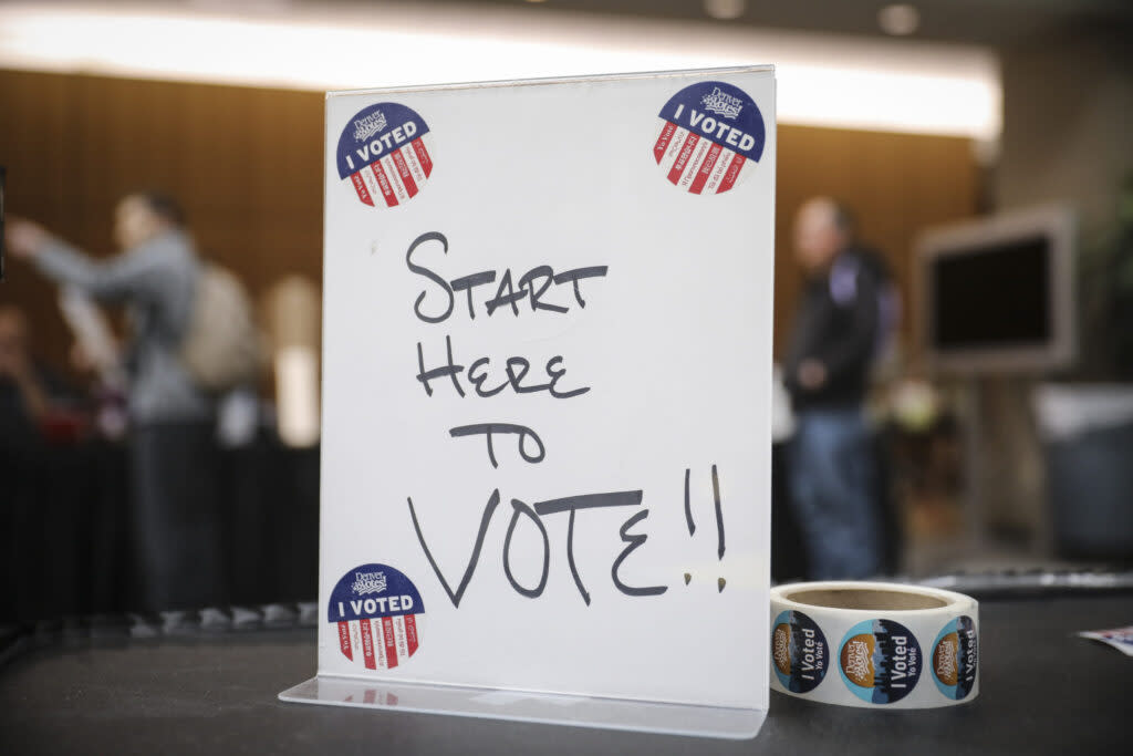the words "Start Here to Vote" are written in back marker on a white board at a voting site