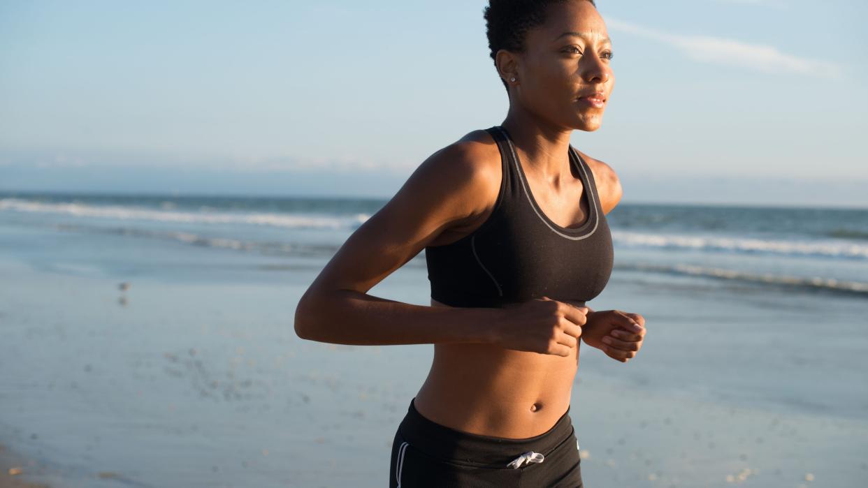 Woman running on the beach in a sports bra