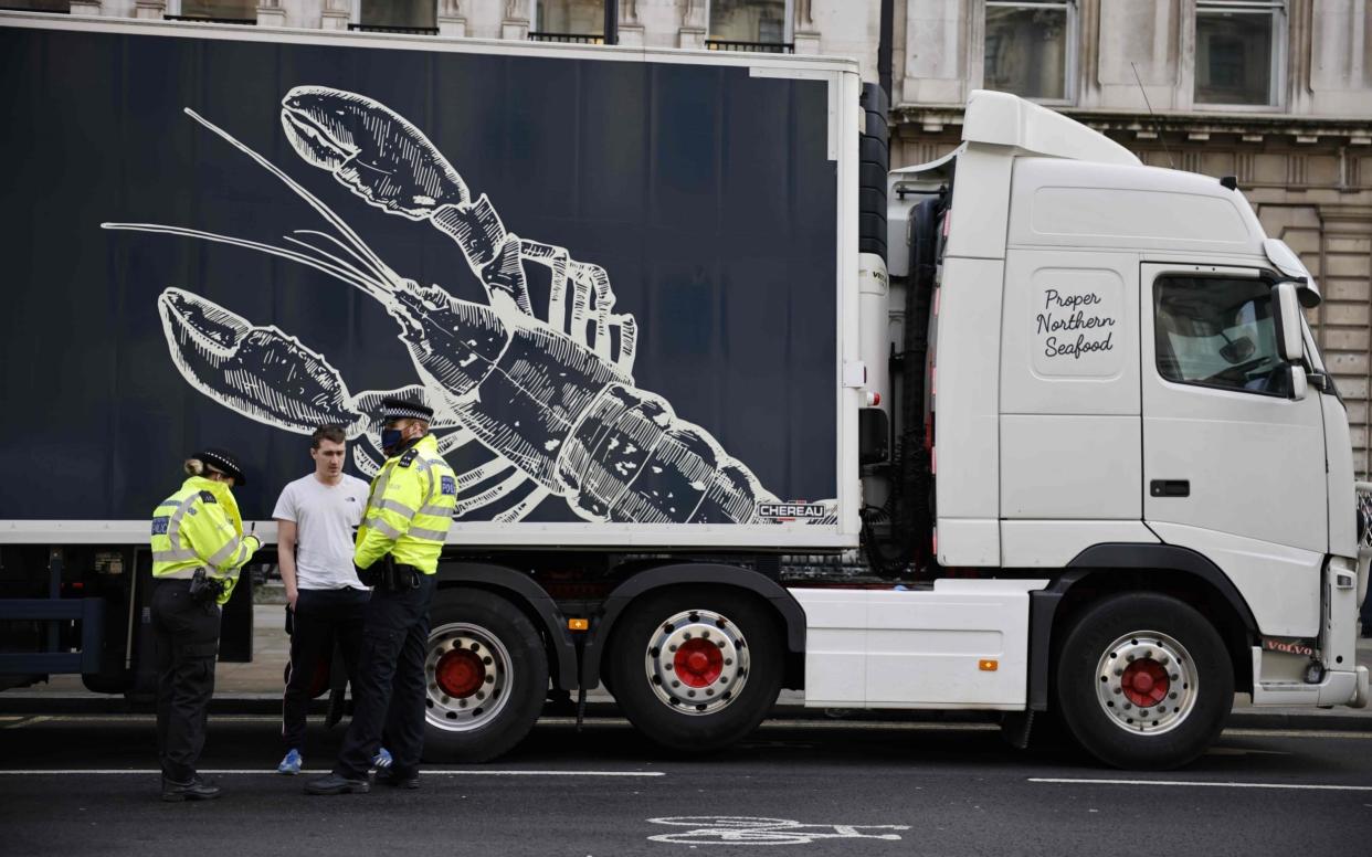 Police officers talk to a driver working in the shellfish industry who brought his truck to central London to protest against post-Brexit red tape and coronavirus restrictions -  AFP