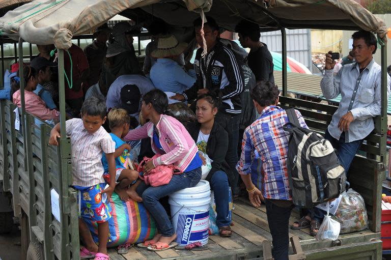 Cambodian migrant workers who recently crossed the border sit in the back of a military truck waiting to be transported back to their home provinces after arriving in the city of Poipet on the Thai-Cambodian border, June 18, 2014