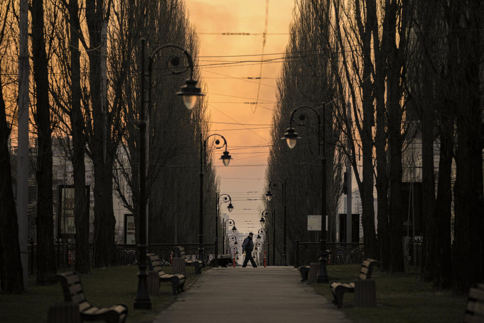 A man walks at dusk in Kyiv, Ukraine, Saturday, March 19, 2022. Russian forces pushed deeper into Ukraine's besieged and battered port city of Mariupol on Saturday, where heavy fighting shut down a major steel plant and local authorities pleaded for more Western help. (AP Photo/Vadim Ghirda)