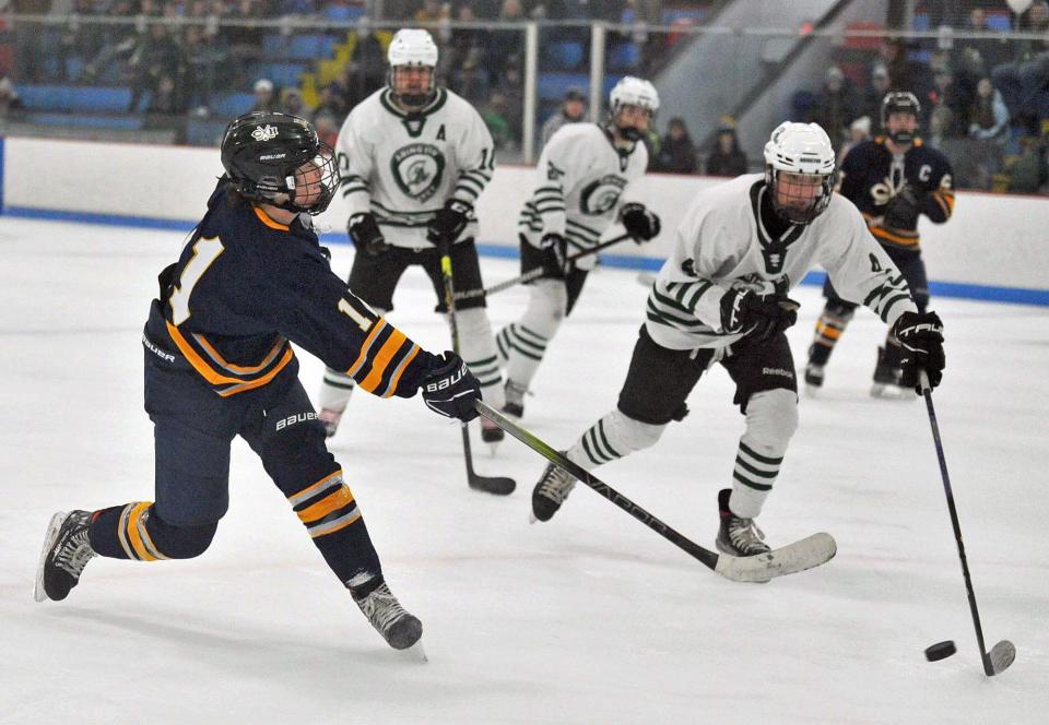 Cohasset/Hull's Taighe Dwyer, left, shoots past Abington defender Travis Swanson, right, during boys high school hockey at the Rockland Ice Rink, Monday, Feb. 12, 2024.