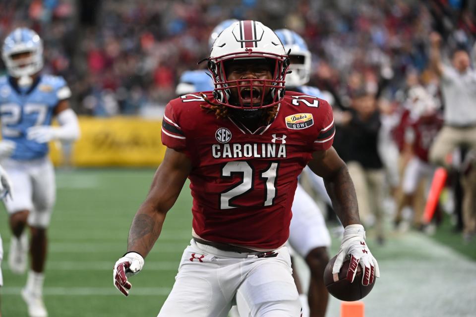 Dec 30, 2021; Charlotte, NC, USA; South Carolina Gamecocks running back Juju McDowell (21) runs for a touchdown as North Carolina Tar Heels linebacker Cedric Gray (33) defensive back Tony Grimes (20) defend in the second quarter during the 2021 Duke's Mayo Bowl at Bank of America Stadium.