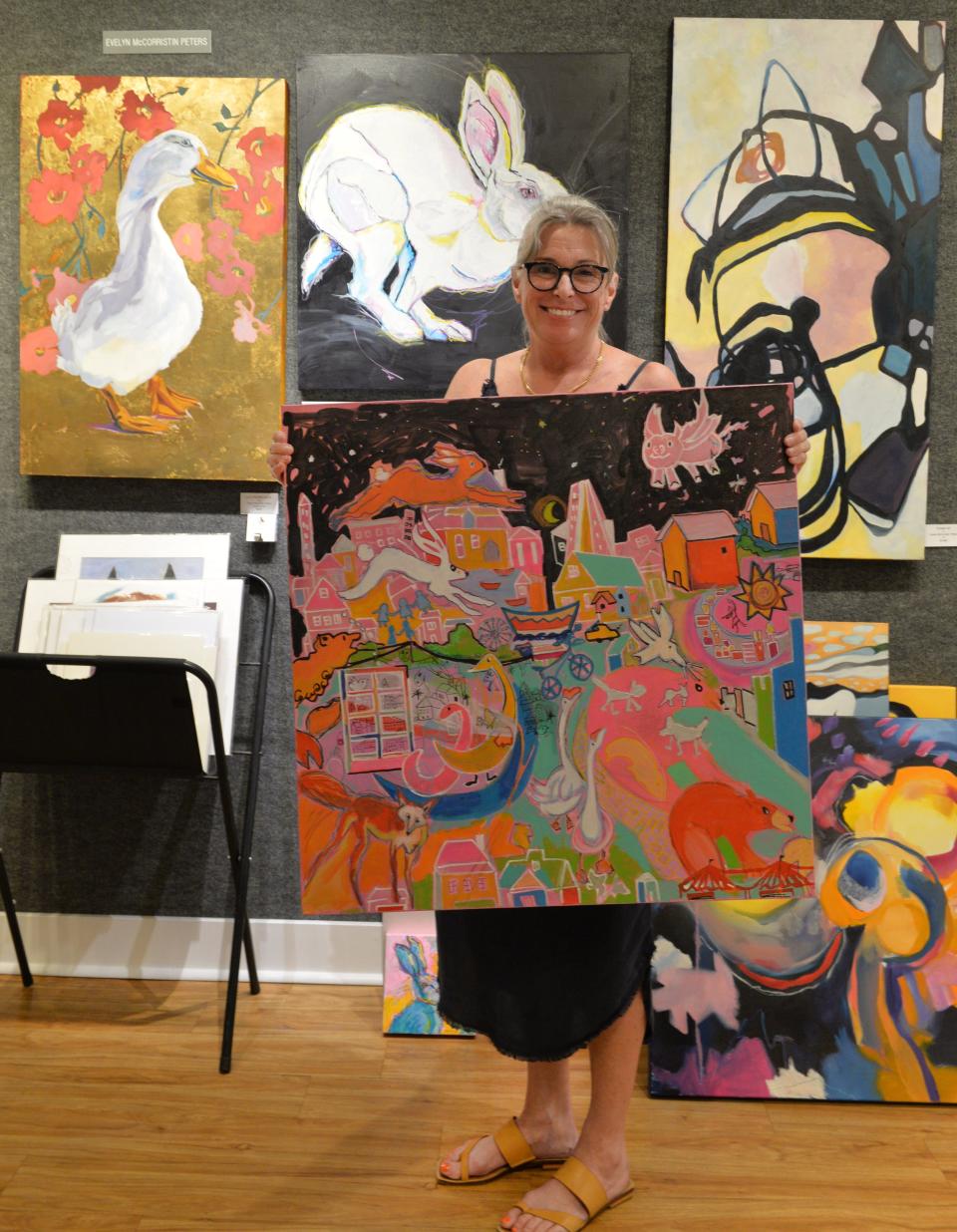 Artist Evelyn McCorristin Peters is treasurer of Art Uptown Gallery on Main St. in Sarasota. Peters holds a mixed media painting titled "Perfection in imperfect dreams" as she stands next to some of her oil paintings on display at the gallery.