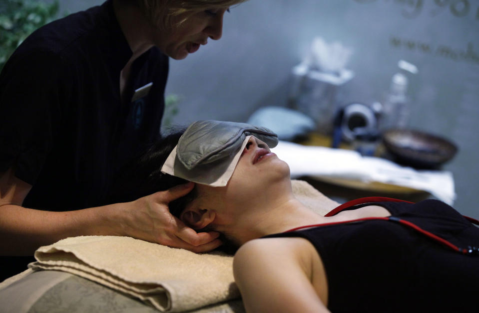 This Aug. 16, 2012 photo shows a woman receiving a spa treatment by a representative of the Aspira Spa, at the Osthoff Resort in Elkhart Lake, Wiisc., in the their booth at the International Spa Association event, in New York. Parties at the spa, treatments for stressed and time-pressed consumers, cross-cultural traditions, and a whole lot of purple _ from lavender-scented treatments to mauve nail polish _ are some of the trends and services that were shown off at the annual International Spa Association meeting held recently in New York. (AP Photo/Richard Drew)