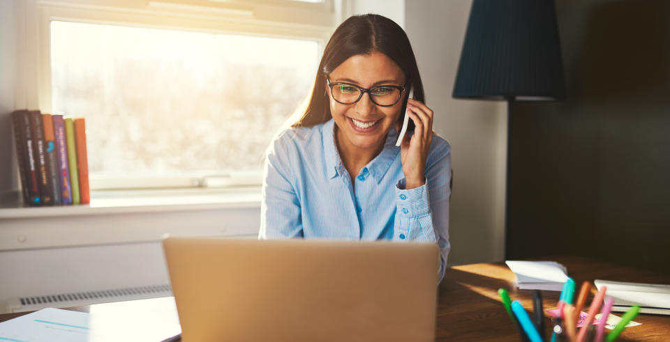 woman on cell phone looking at laptop