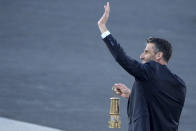 Tony Estanguet, President of Paris 2024, waves while holding the Olympic flame during the flame handover ceremony at Panathenaic stadium, where the first modern games were held in 1896, in Athens, Friday, April 26, 2024. On Saturday the flame will board the Belem, a French three-masted sailing ship, built in 1896, to be transported to France. (AP Photo/Petros Giannakouris)