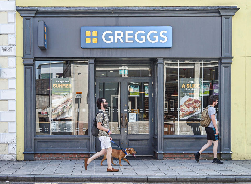 LISBURN, UNITED KINGDOM - 2021/07/18: Man with a dog walk by Greggs Hot Food Store on Bow Street. (Photo by Michael McNerney/SOPA Images/LightRocket via Getty Images)