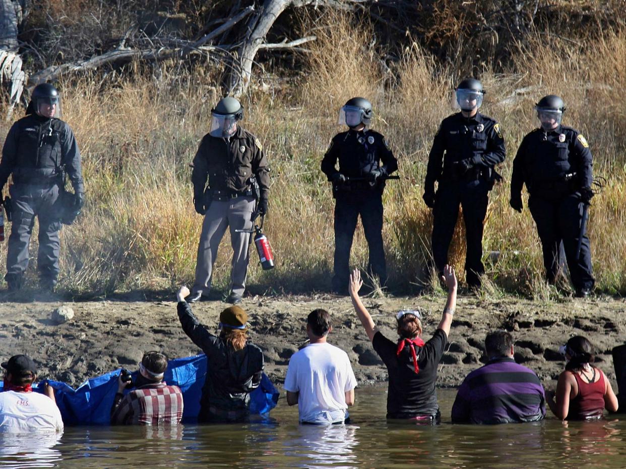 Dozens of protestors demonstrating against the expansion of the Dakota Access Pipeline wade in cold creek waters confronting local police, near Cannon Ball, North Dakota in November 2016 (AP Photo/John L. Mone File)