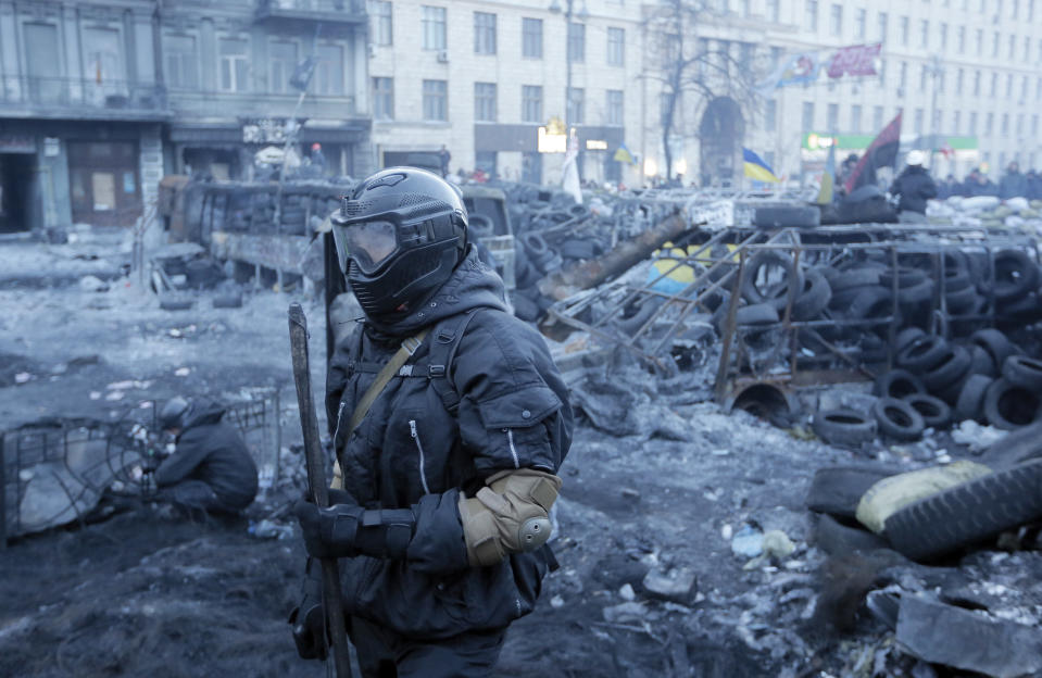 A protester guards the barricades in front of riot police in Kiev, Ukraine, Monday, Jan. 27, 2014. Ukraine's justice minister is threatening to call for a state of emergency unless protesters leave her ministry building, which they occupied during the night. The seizure of the building early Monday underlined how anti-government demonstrators are increasingly willing to take dramatic action as they push for the president's resignation and other concessions. Protesters now occupy four sizable buildings in downtown Kiev, including the city hall. (AP Photo/Efrem Lukatsky)