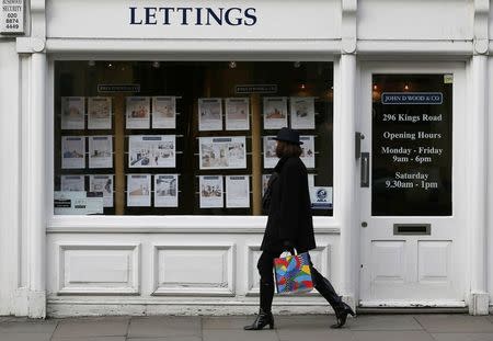 A woman walks past an estate agent in Chelsea, London, in this file photograph dated February 7, 2013. REUTERS/Stefan Wermuth/Files