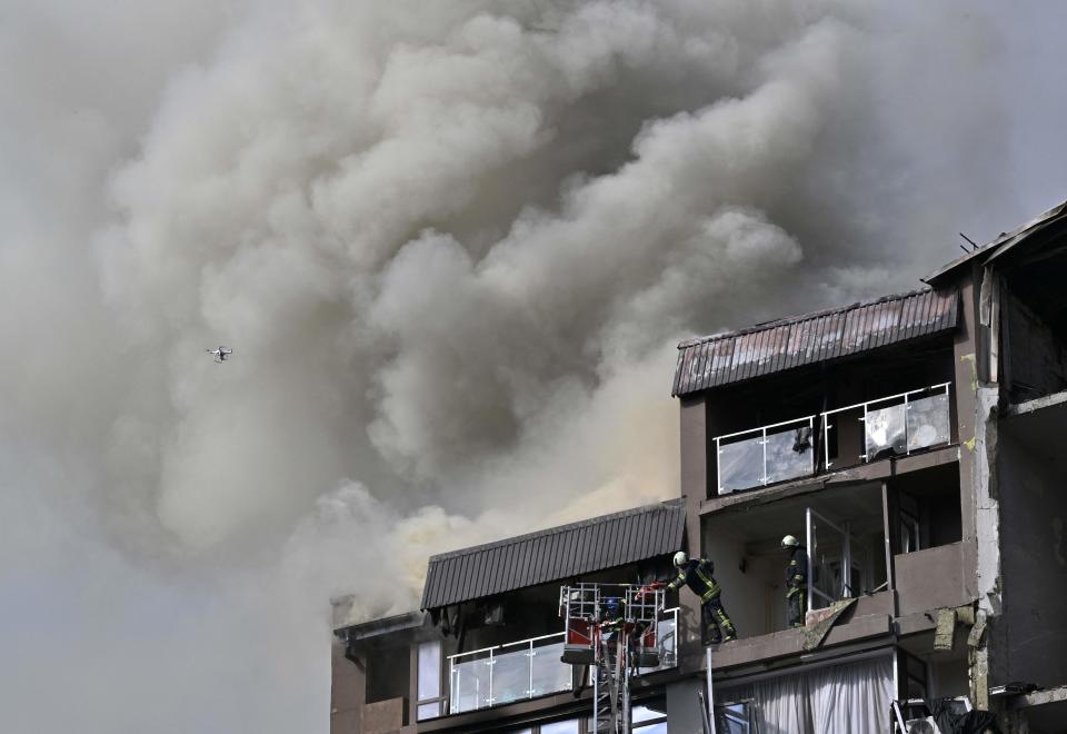 TOPSHOT - Rescuers and firefighters work in a damaged residential building, hit by Russian missiles in Kyiv on June 26, 2022, amid Russian invasion of Ukraine. - 