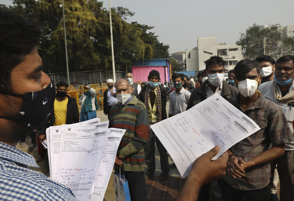 A health worker hands out COVID-19 test results in New Delhi, India, Thursday, Feb. 11, 2021. When the coronavirus pandemic took hold in India, there were fears it would sink the fragile health system of the world’s second-most populous country. Infections climbed dramatically for months and at one point India looked like it might overtake the United States as the country with the highest case toll. But infections began to plummet in September, and experts aren’t sure why. (AP Photo/Manish Swarup)