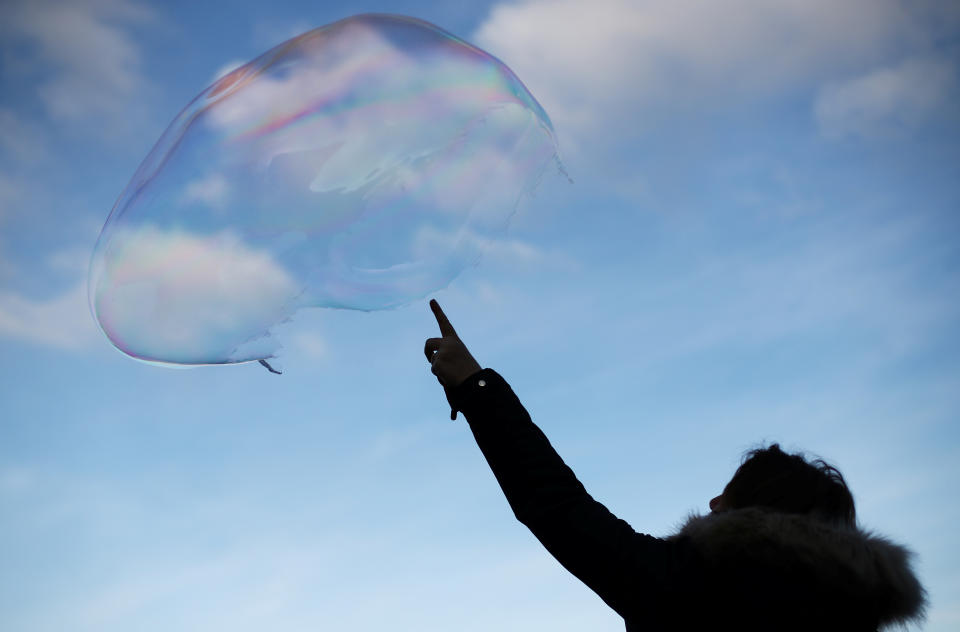 A woman bursts a large soap bubble as it floats through the air in central London, Britain, December 27, 2019. REUTERS/Hannah McKay