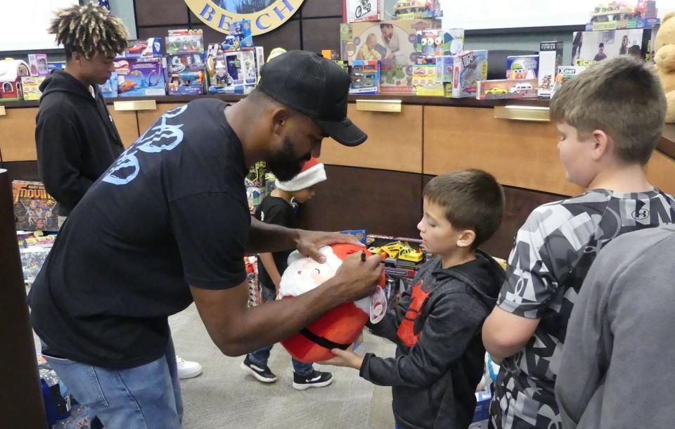 Miami Dolphins running back Raheem Mostert signs a toy during his Christmas gift giveaway Tuesday in his hometown of New Smyrna Beach.