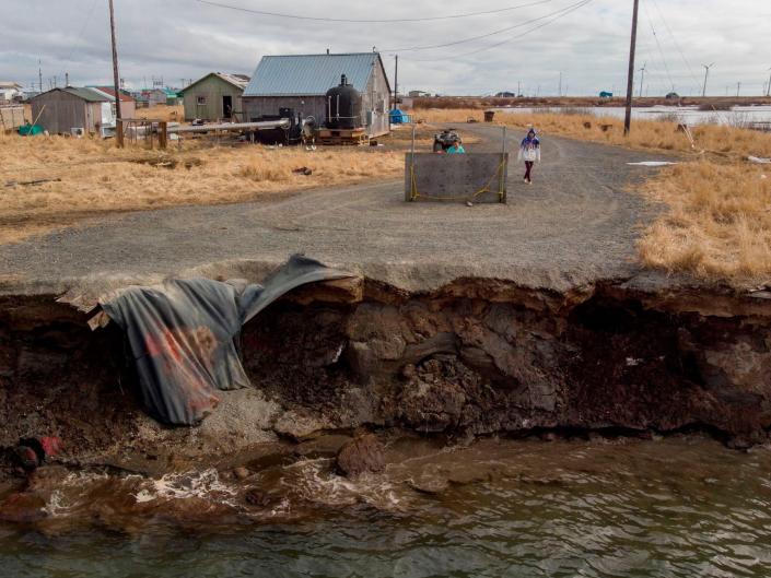 gravel road abruptly ends crumbling into running water two feet below in rural setting with a few homes