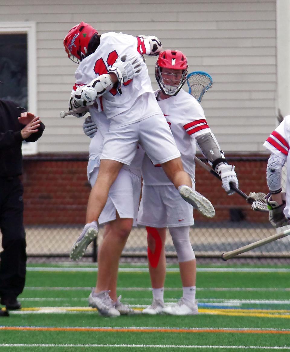 #11 Jayson Kelleher of Bridgewater/Raynham leaps onto teammate Colin Carfagna who just scored for the Trojans in the 2nd half of the lacrosse game against Old Rochester on Thursday, April 11, 2024.