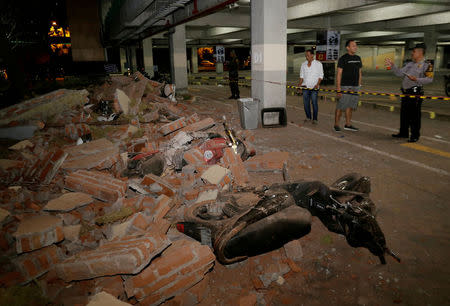 A policeman examines debris that fell and crushed parked motorbikes following a strong earthquake on nearby Lombok island, at a shopping center in Kuta, Bali, Indonesia. REUTERS/Johannes P. Christo