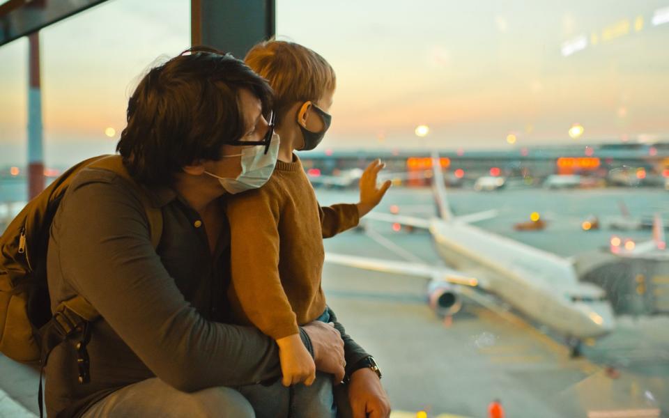 Father and son wearing masks at airport - Getty