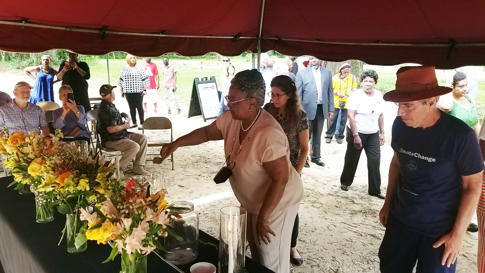 State Rep. Yvonne Hayes Hinson delicately places soil in a jar at the Micanopy Community Remembrance Project's soil collection ceremony.