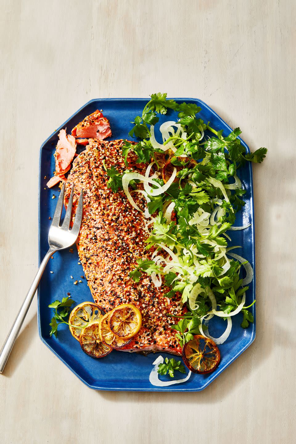 everything bagel crusted salmon with a side salad on a blue plate