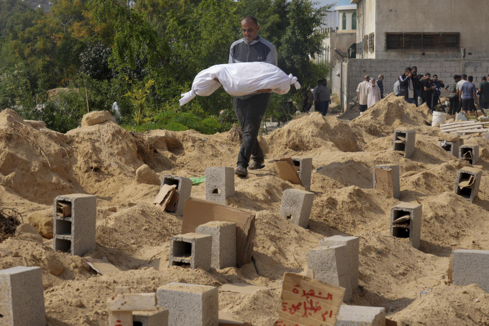 FILE - Palestinians bury the bodies of their relatives killed in the Israeli bombardment of the Gaza Strip, at a cemetery in Deir Al-Balah, Gaza, Monday, Oct. 23, 2023. Palestinians say the devastating war between Israel and Hamas is robbing them not only of their loved ones but also of the funeral rites that long have offered mourners some dignity and closure in the midst of grief. (AP Photo/Hatem Moussa, File)