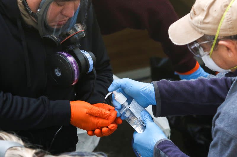 Members of a Servpro cleaning crew use hand sanitizer as they exit the Life Care Center of Kirkland, the Seattle-area nursing home at the epicenter of one of the biggest coronavirus outbreaks in the United States, in Kirkland